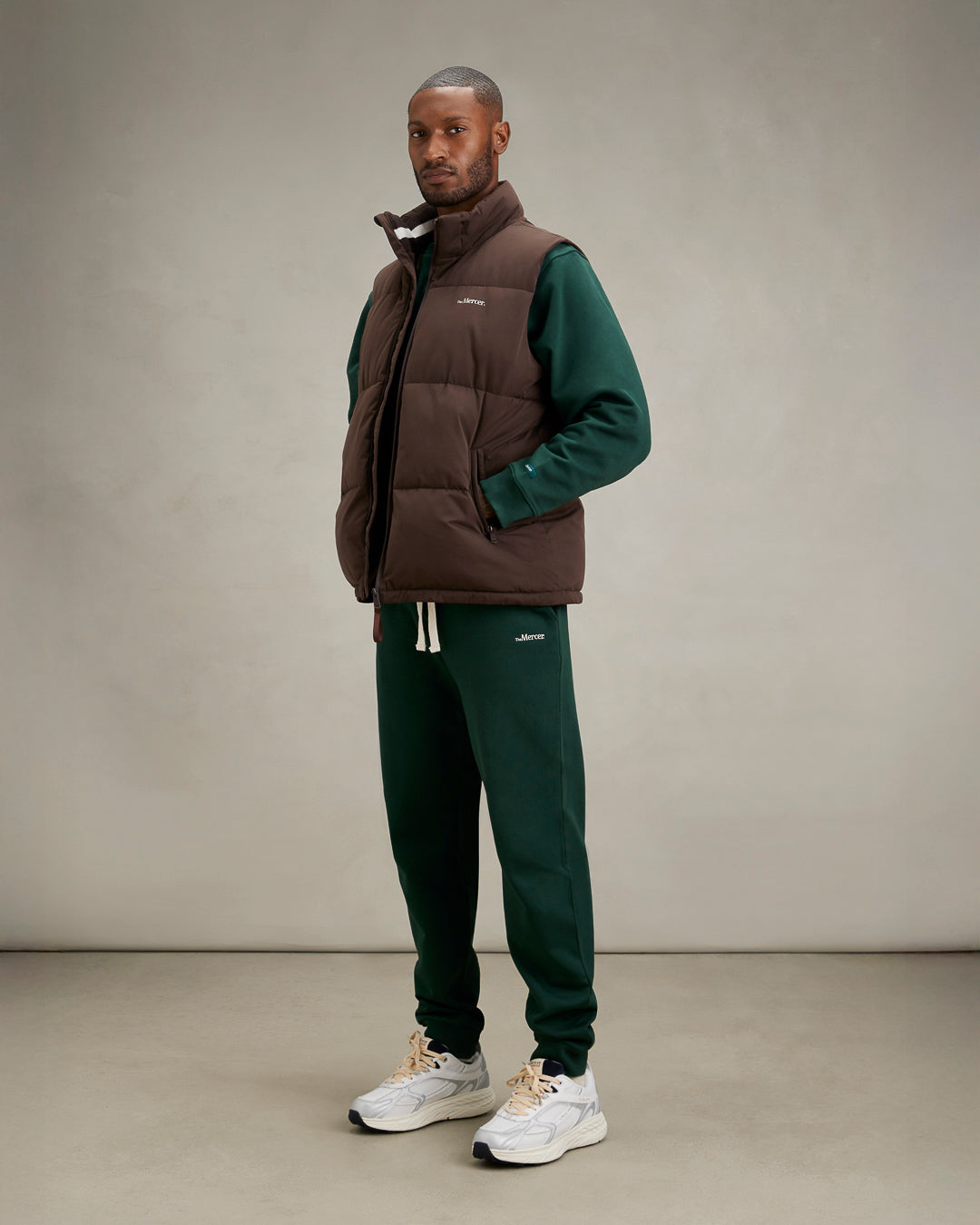 the mercer brand re-run max sneaker track and field white sneaker with cream laces and small navy details styled for men with sweat suit and bodywarmer brown