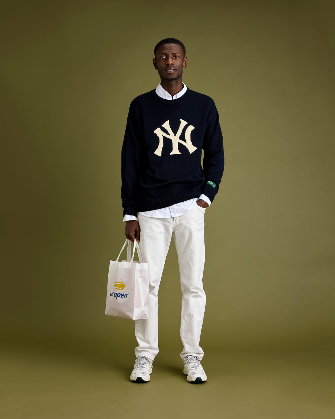 A man is wearing The Mercer 47 knit in navy with The Oxford in white underneath. His shoes are The Re-Run Evo in white.