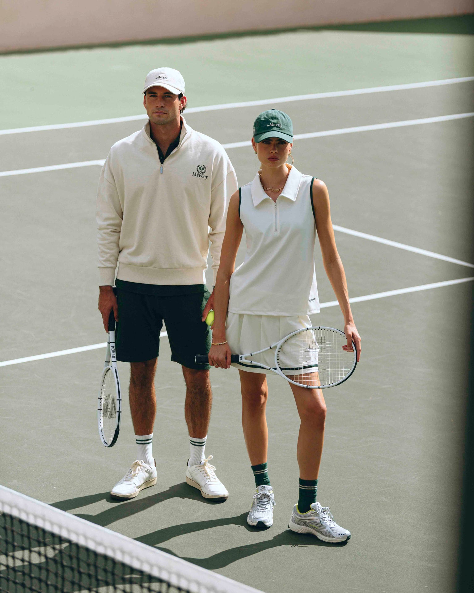 lifestyle shot of male and female model on tennis court wearing the mercer brand apparel and sneakers from the mercer brand