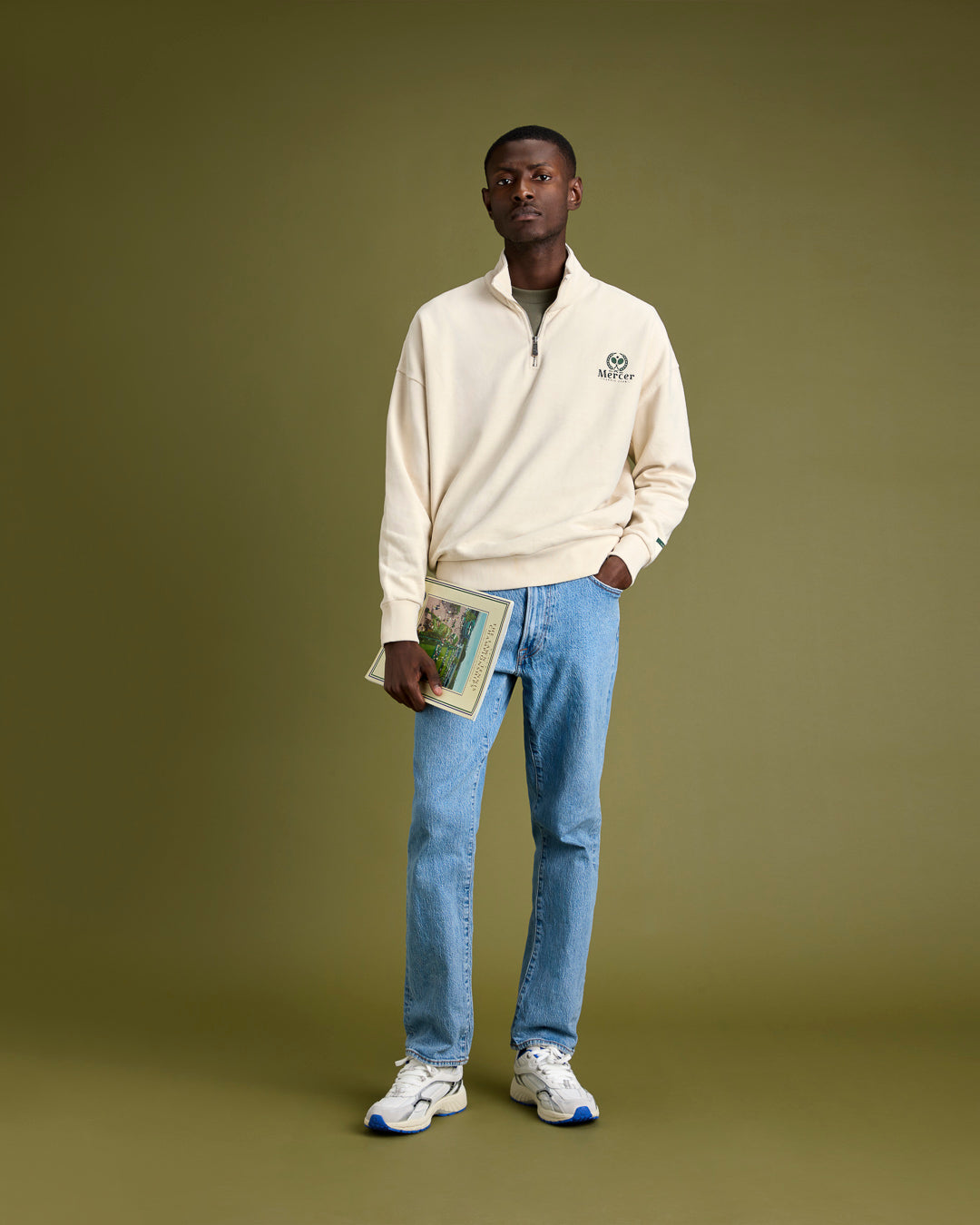 A man is wearing The Mercer Tennis Quarter zip with The Re-Run White/Silver in White/Blue.