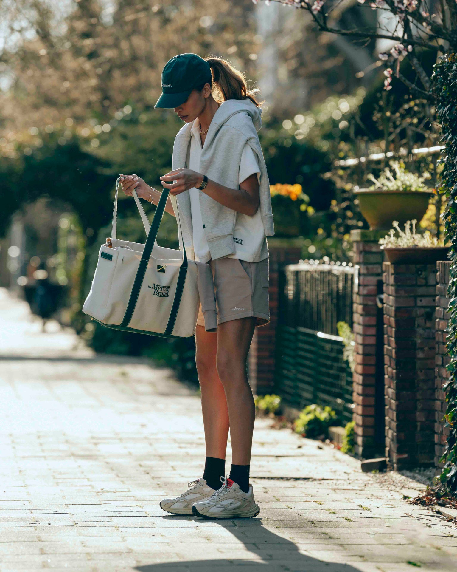lifestyle shot of women looking inside of her the mercer brand bag and wearing The Re-Run Vibram in Off White