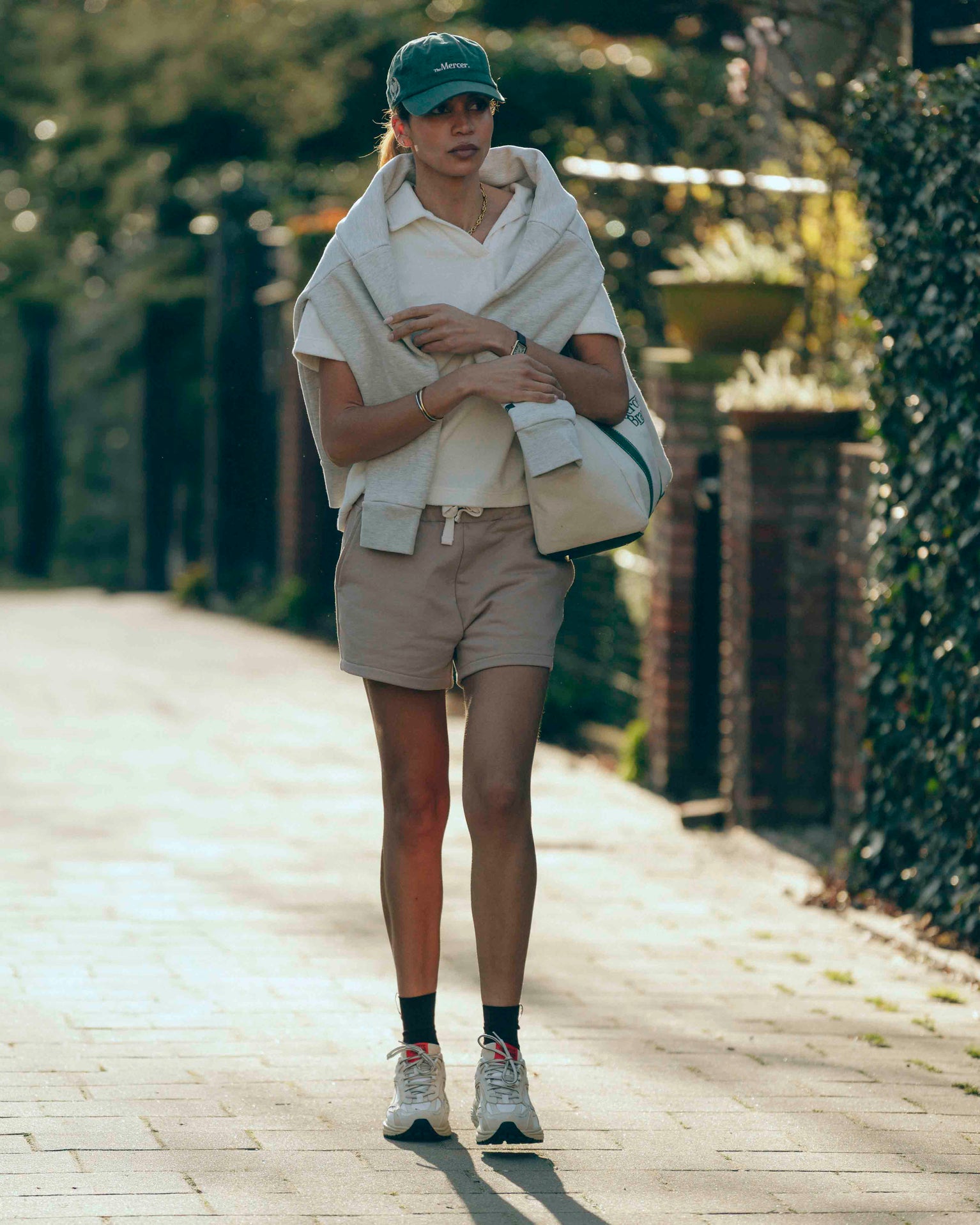 lifestyle shot of women wearing a green the mercer brand cap, short and The Re-Run Vibram in Off White
