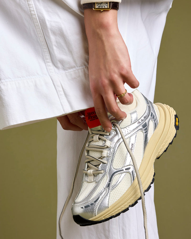 On foot model shot of The Re-Run Vibram in Silver with orange detail on the tongue of the sneaker by the mercer brand