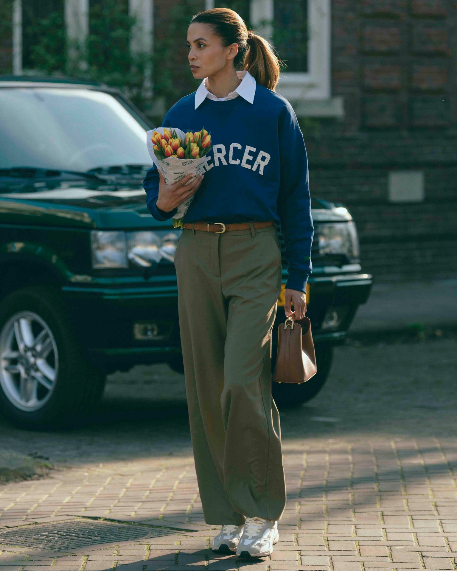 A woman is wearing The Re-Run Desert 2.0 in sand with the Mercer Logo Sweat.