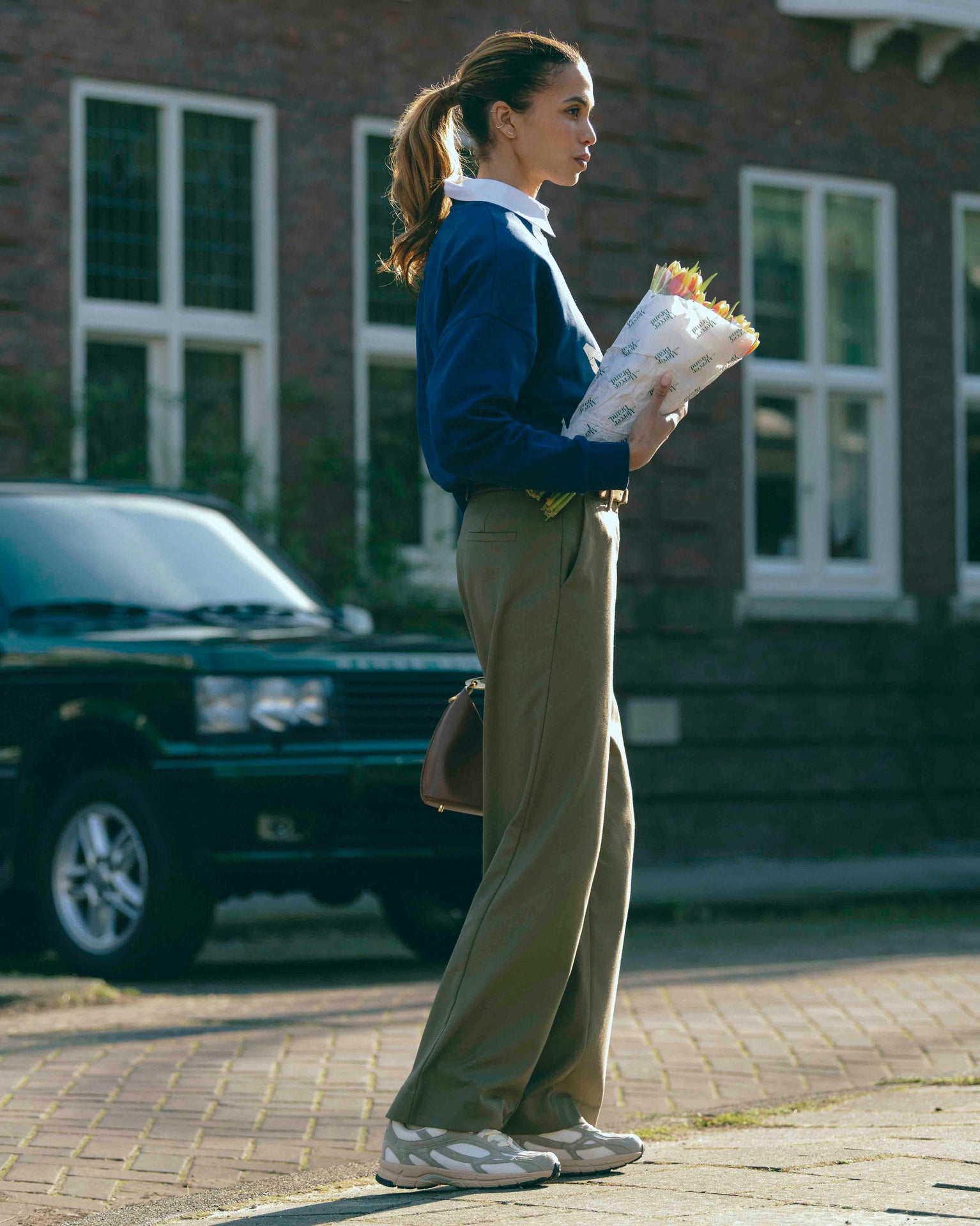 A woman is wearing The Re-Run Desert 2.0 in sand with the Mercer Logo Sweat.