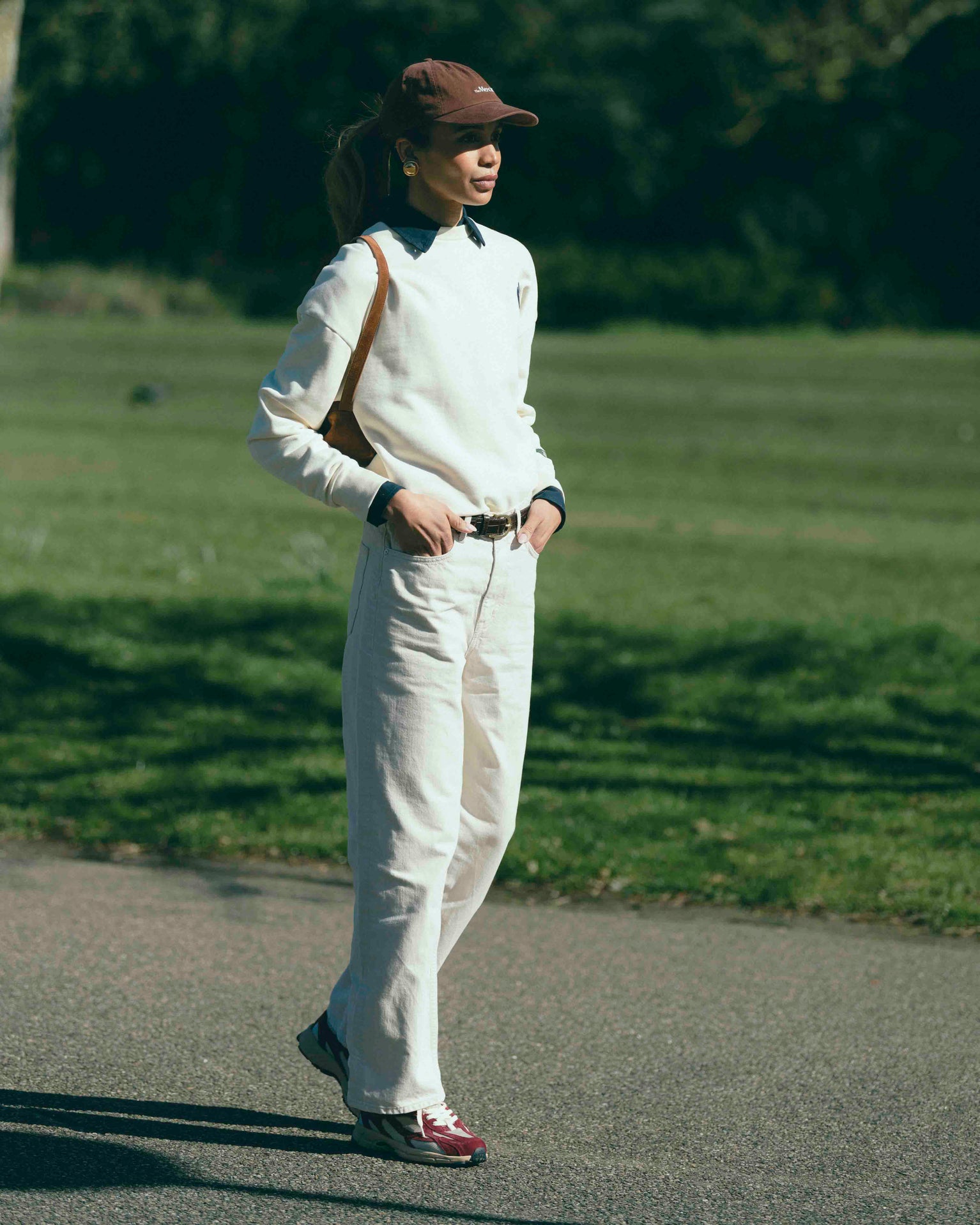A woman is wearing The Subway Sweater and The Mercer Cap paired with The Re-Run desert 2.0 in bordeaux.