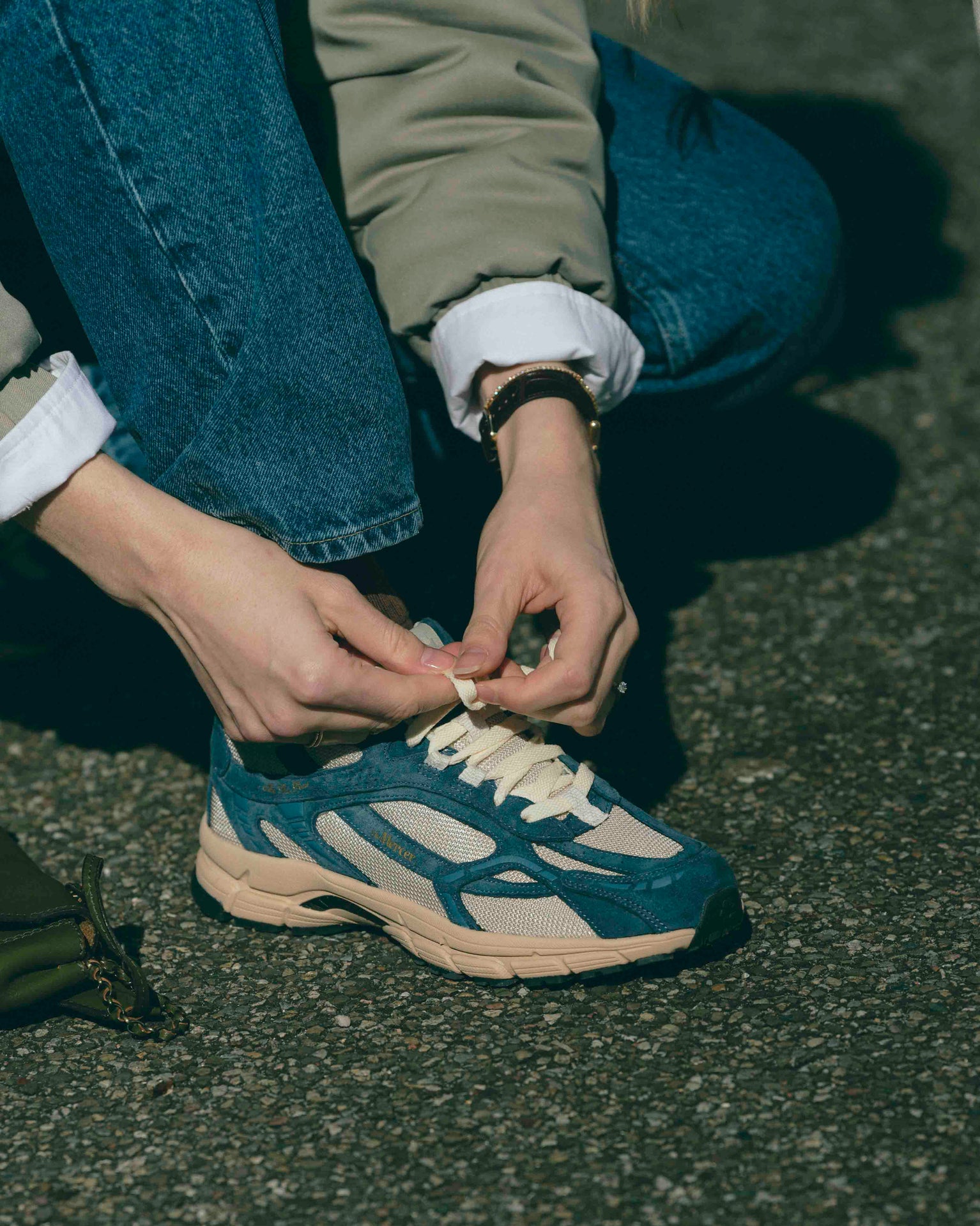 A woman is tying the laces of her The Re-Run Desert 2.0 in blue.