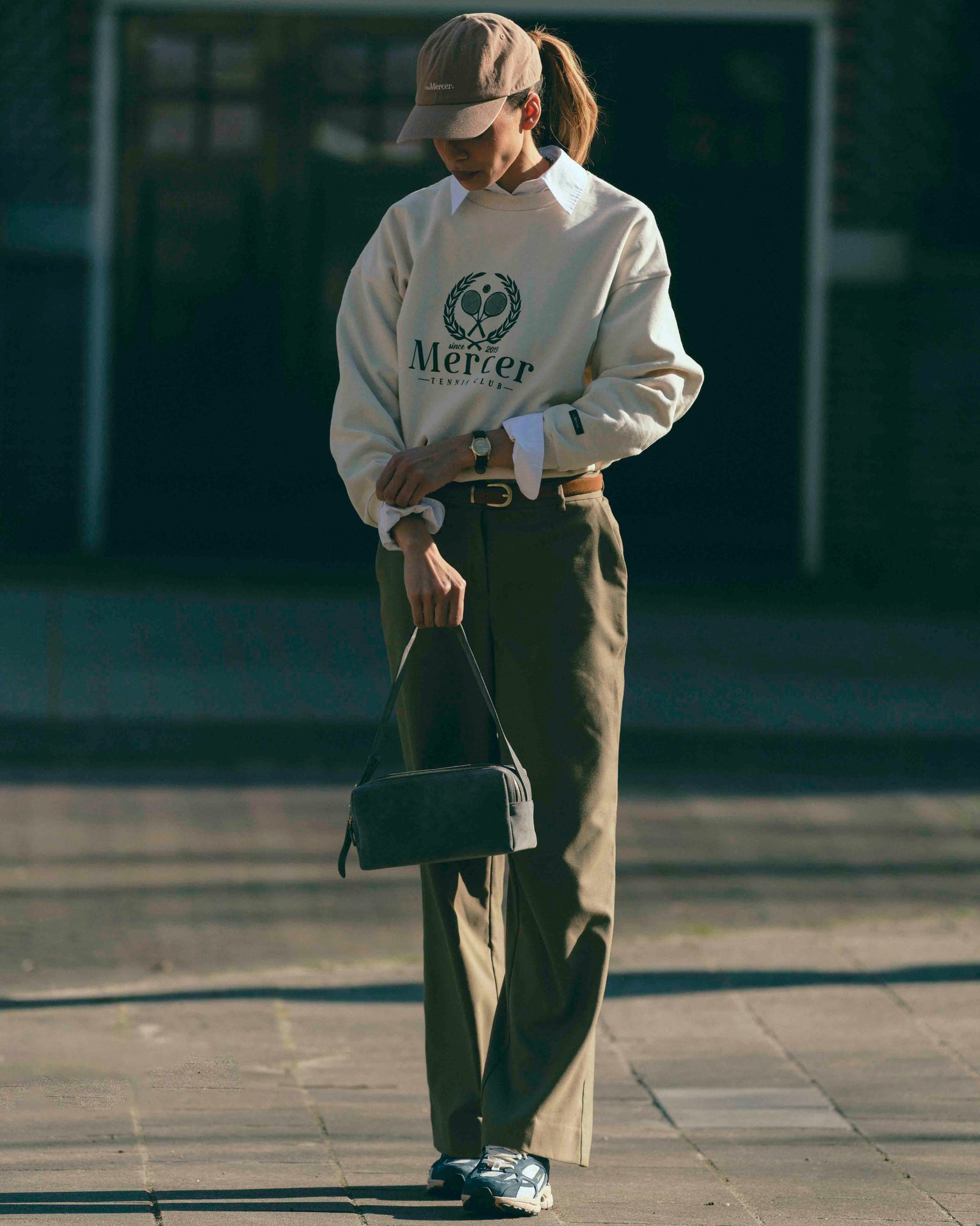 A woman is wearing The Re-Run Desert 2.0 in blue with The Mercer Tennis Sweater and The Mercer cap.