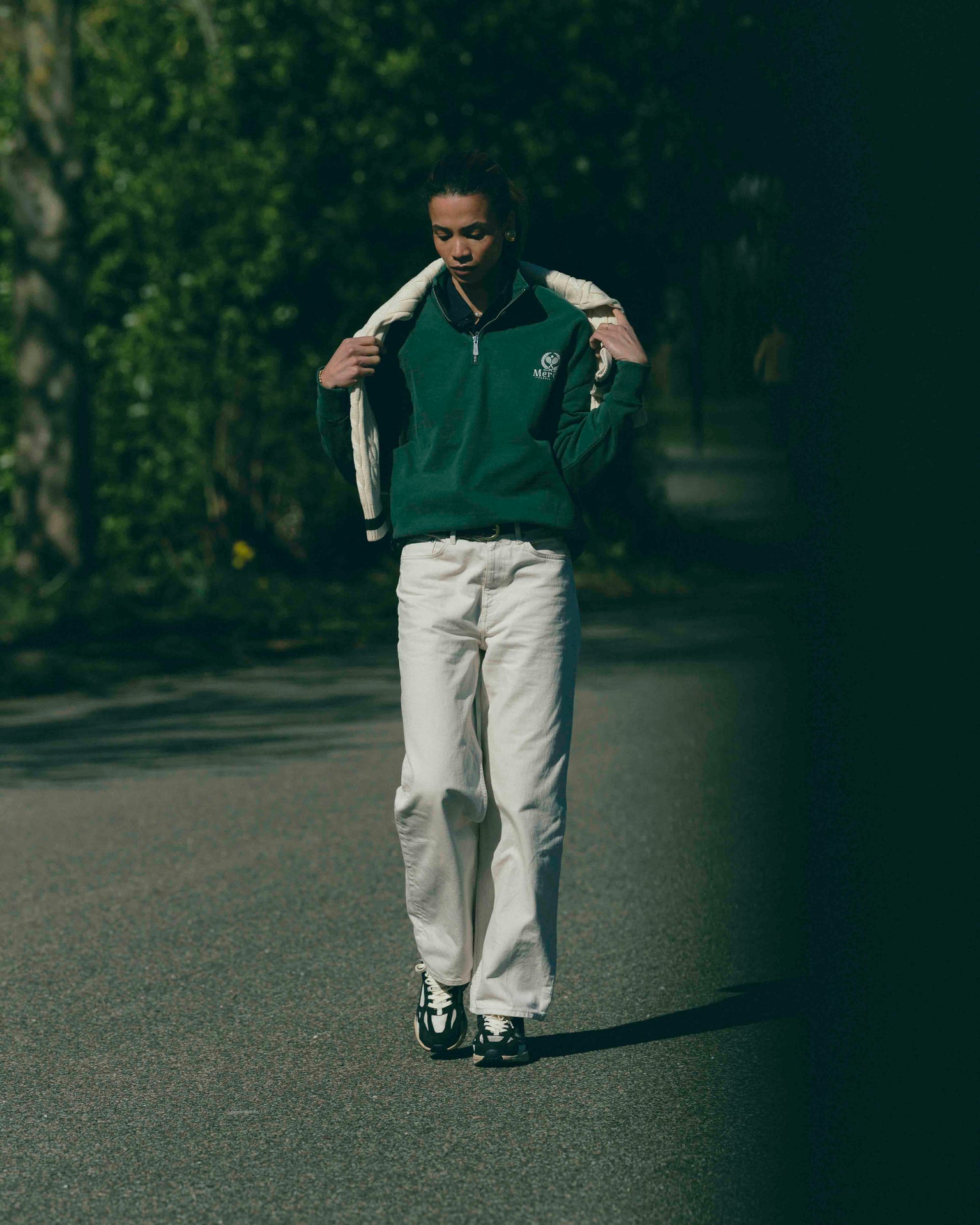 A woman is wearing The Mercer Tennis Quarter zip paired with The RE-Run Desert 2.0 in Antracite. 