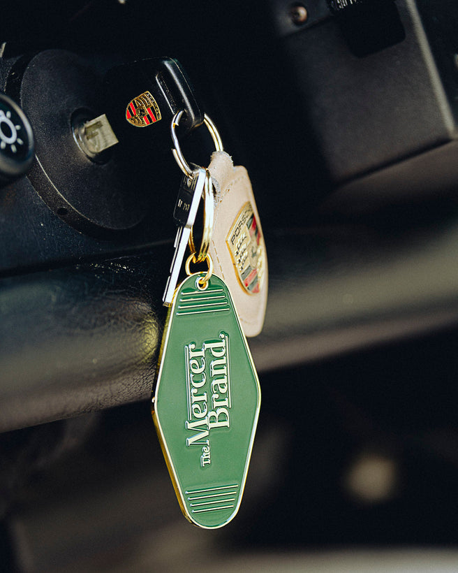 the mercer brand keychain green with gold details with logo and the mercer dog