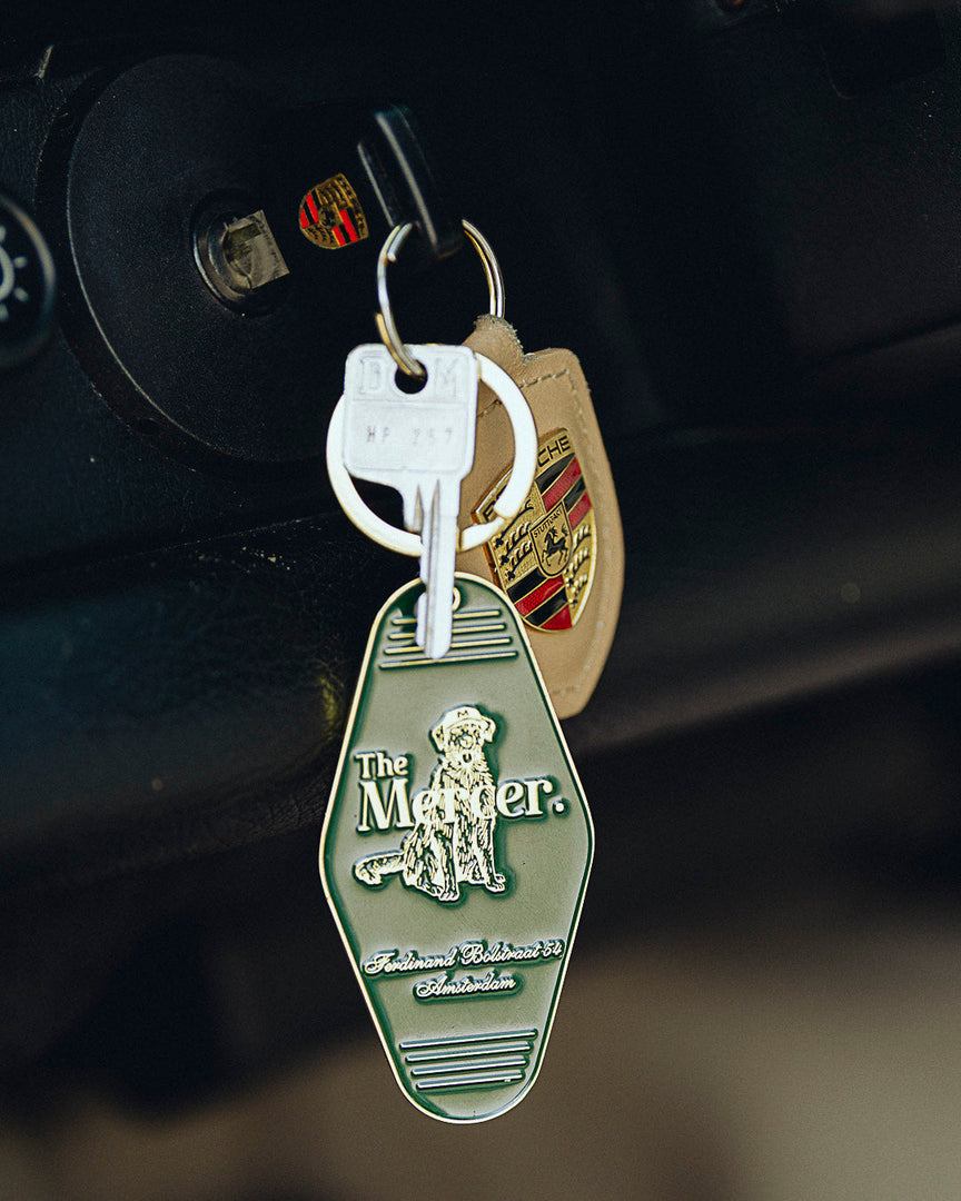the mercer brand keychain green with gold details with logo and the mercer dog