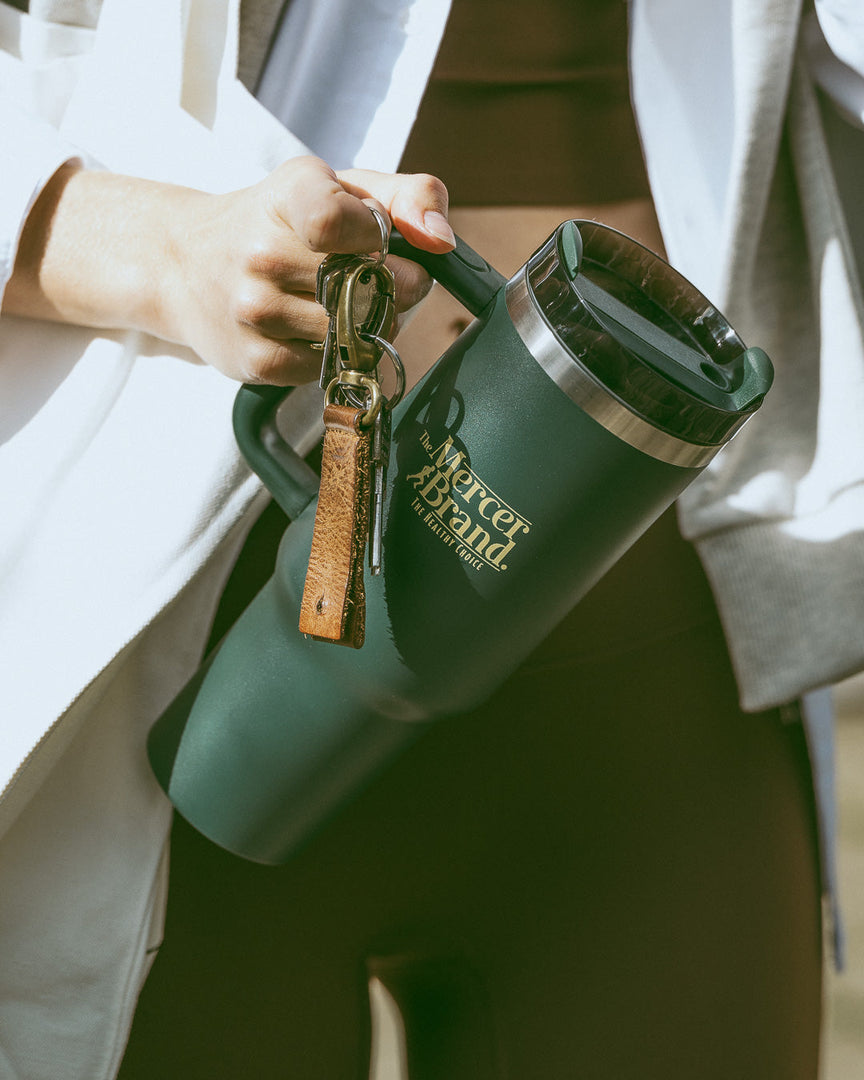 The Mercer Brand green tumbler with logo on light grey background