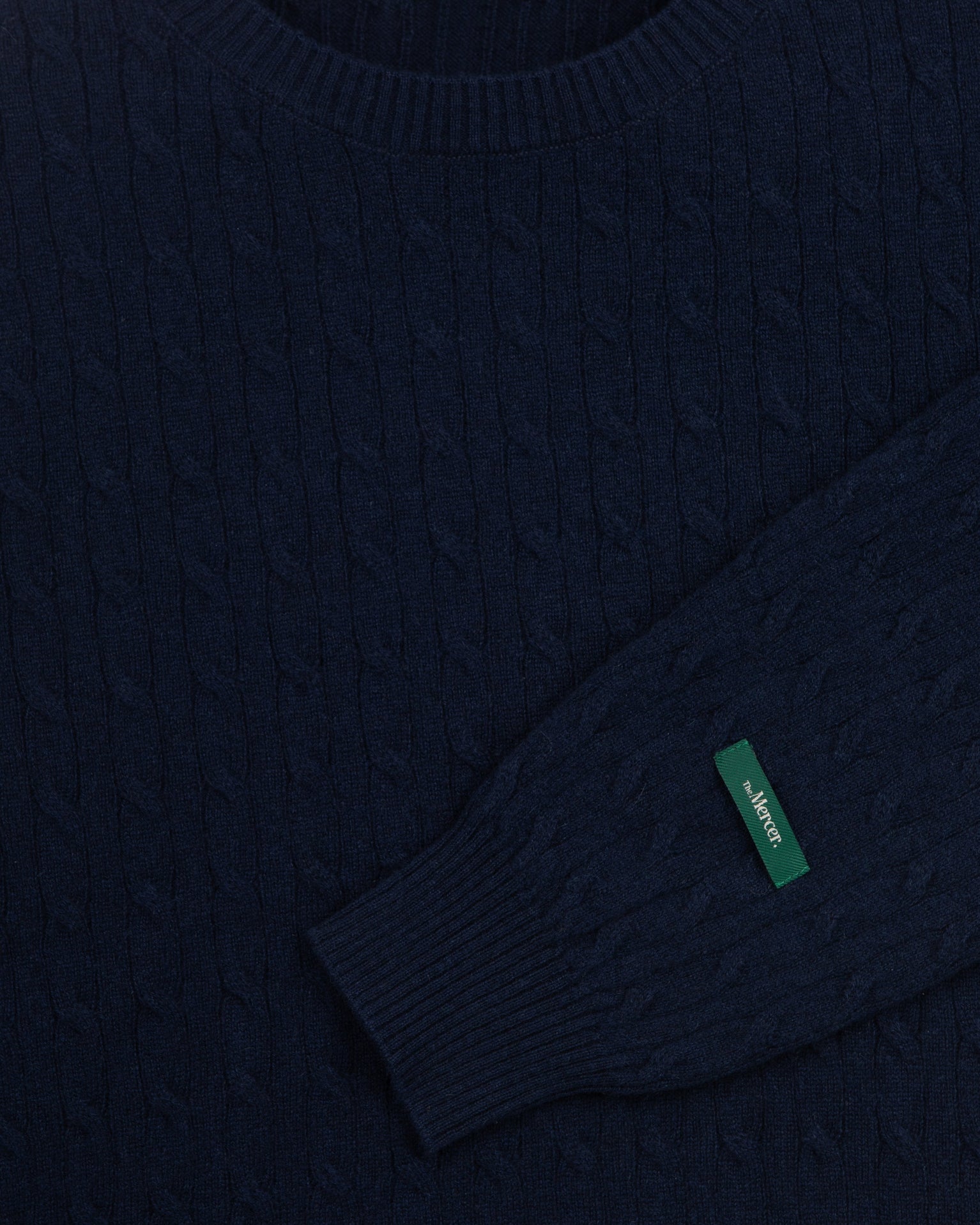 the mercer brand cable knit sweater cashmere navy with green logo on sleeve product photo front 