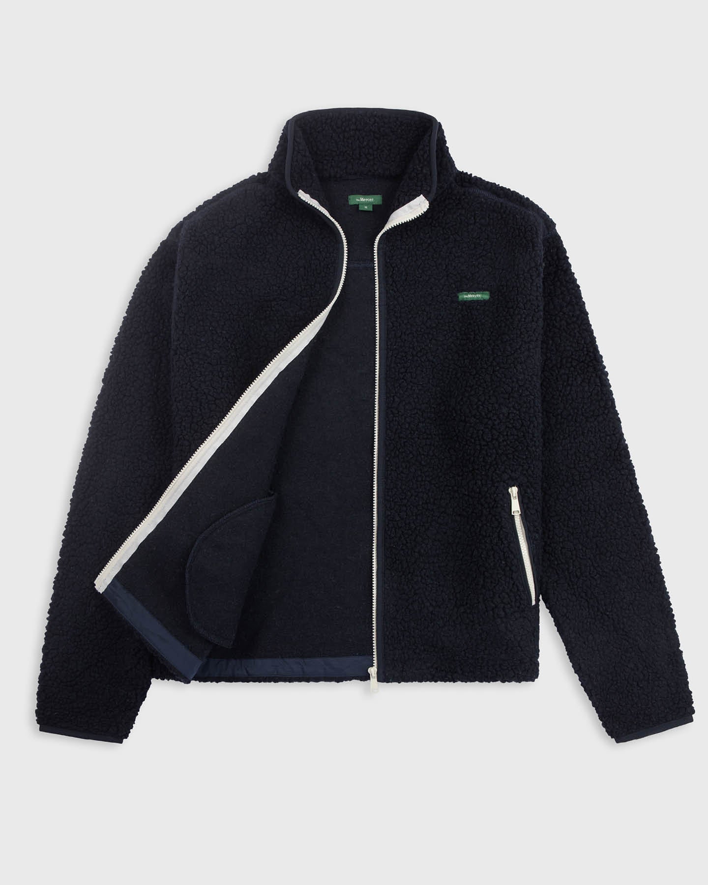 The mercer brand wool zip navy with white zippers and green logo front