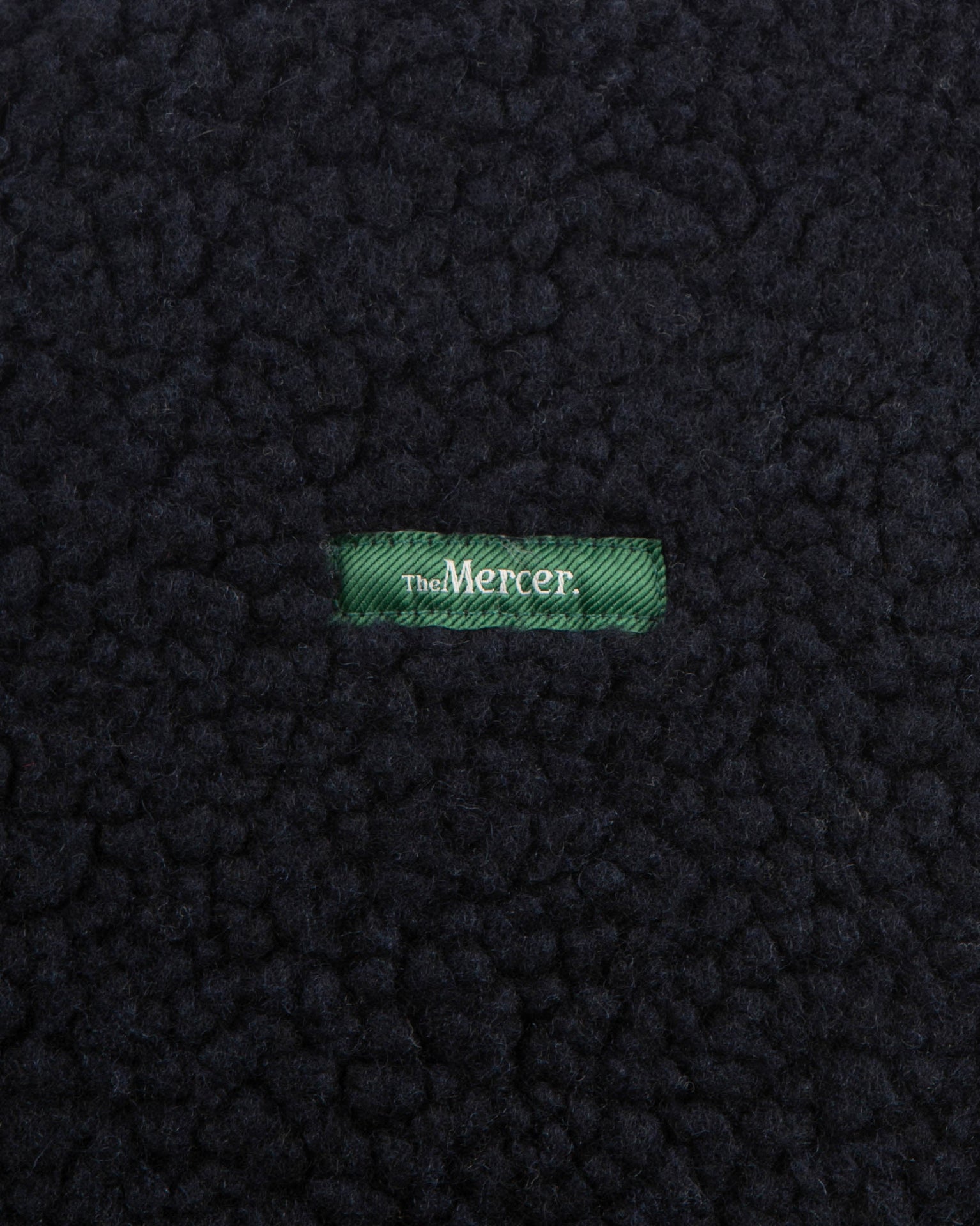 The mercer brand wool zip navy with white zippers and green logo front