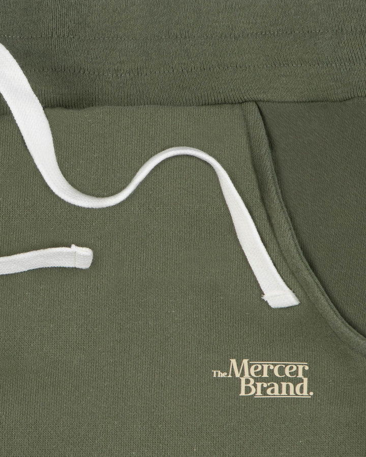 Green The Mercer Brand sweatpants with white drawstring on a light grey background