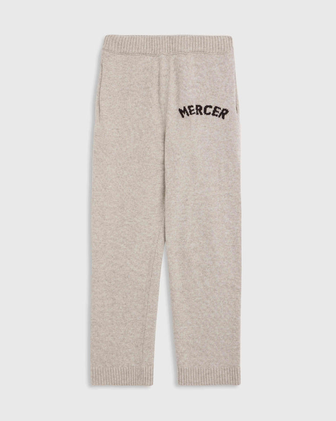 The Mercer Knit Pants Women in light sand, featuring an elastic waistband and the word MERCER embroidered in black on the upper left thigh.
